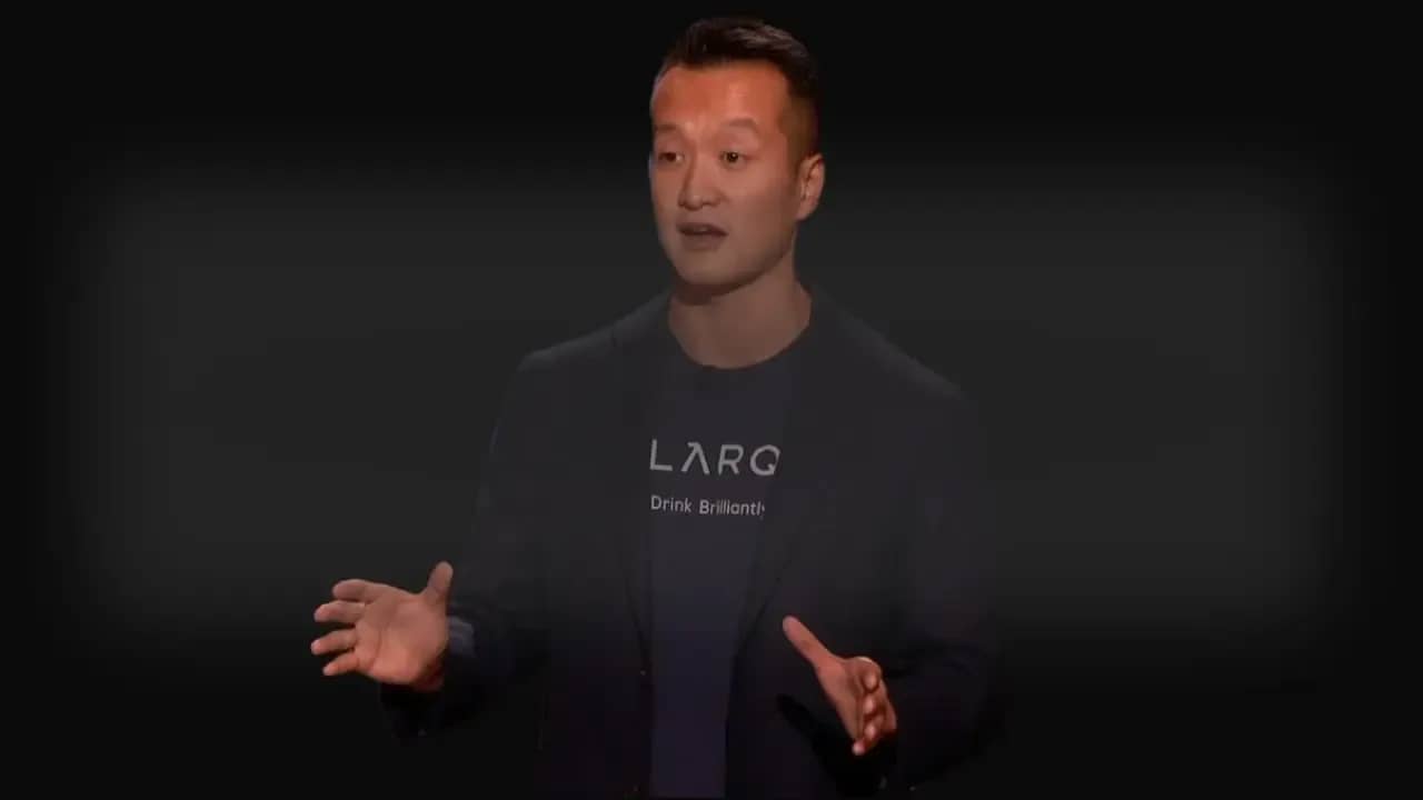 Justin Wang, CEO of LARQ, pitching his self-cleaning water bottle on Shark Tank, wearing a LARQ-branded shirt and blazer.