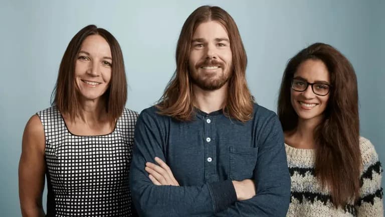 Dan Price, CEO of Gravity Payments, standing with two employees after taking a 94% pay cut to raise employee salaries to $70K.
