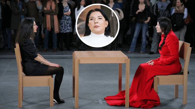 Marina Abramović sits silently across from a visitor during her 2010 MoMA performance The Artist Is Present, exploring human connection through stillness and eye contact.