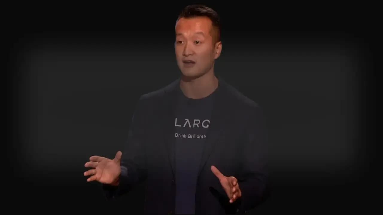 Justin Wang, CEO of LARQ, pitching his self-cleaning water bottle on Shark Tank, wearing a LARQ-branded shirt and blazer.