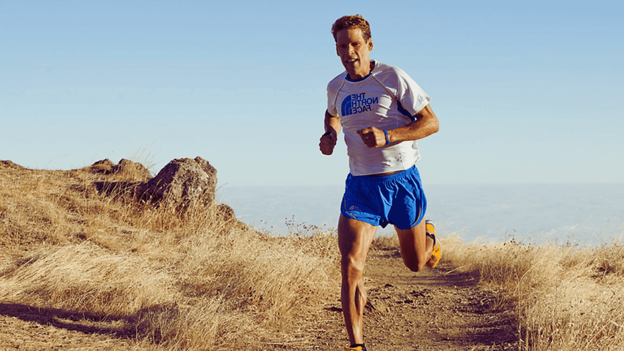 Dean Karnazes running on a mountain trail during an ultramarathon, known for completing 350 miles without sleep