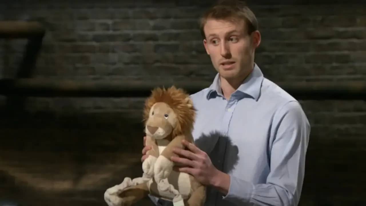 James Roupell holding a Bobo Buddies lion plush during his Dragons' Den UK pitch for multifunctional children’s travel toys.