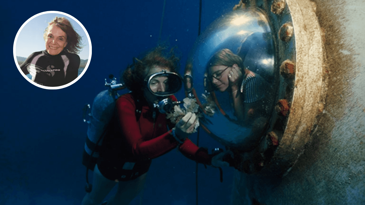 Sylvia Earle scuba diving during an underwater mission, showing coral to a researcher inside a habitat window
