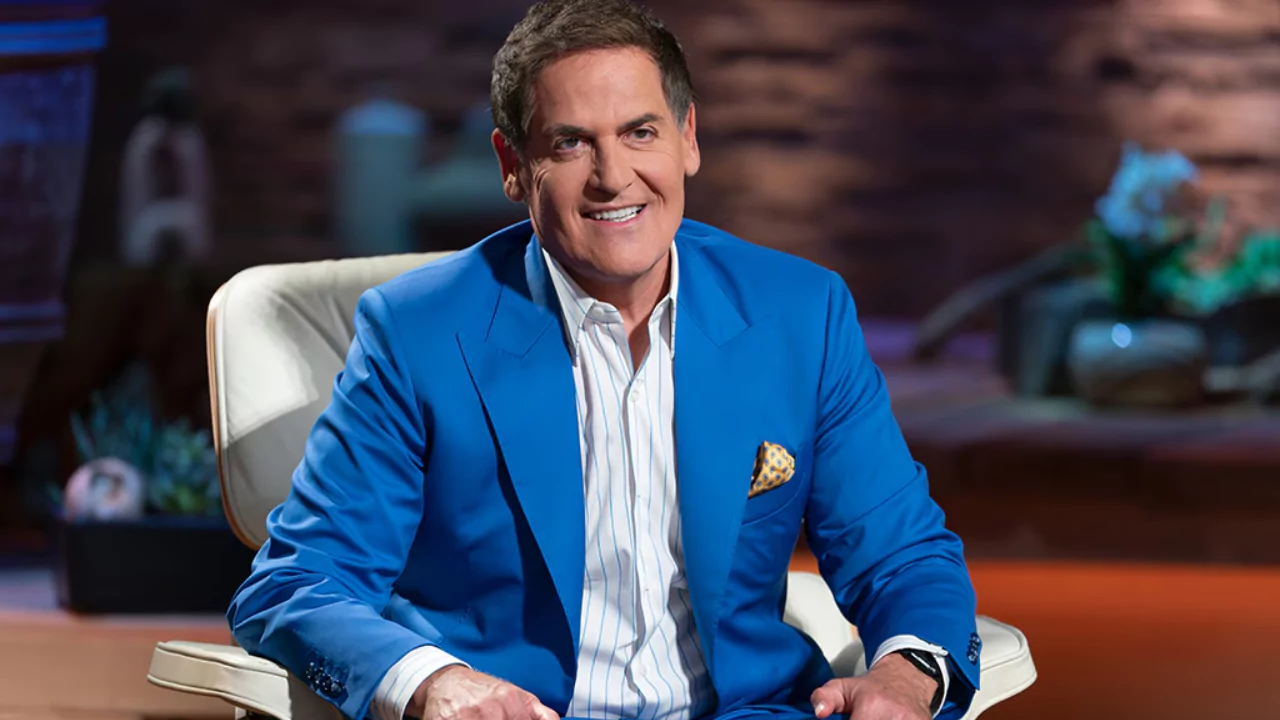 Mark Cuban smiling on the Shark Tank set after earning millions from his $33 million startup investments.