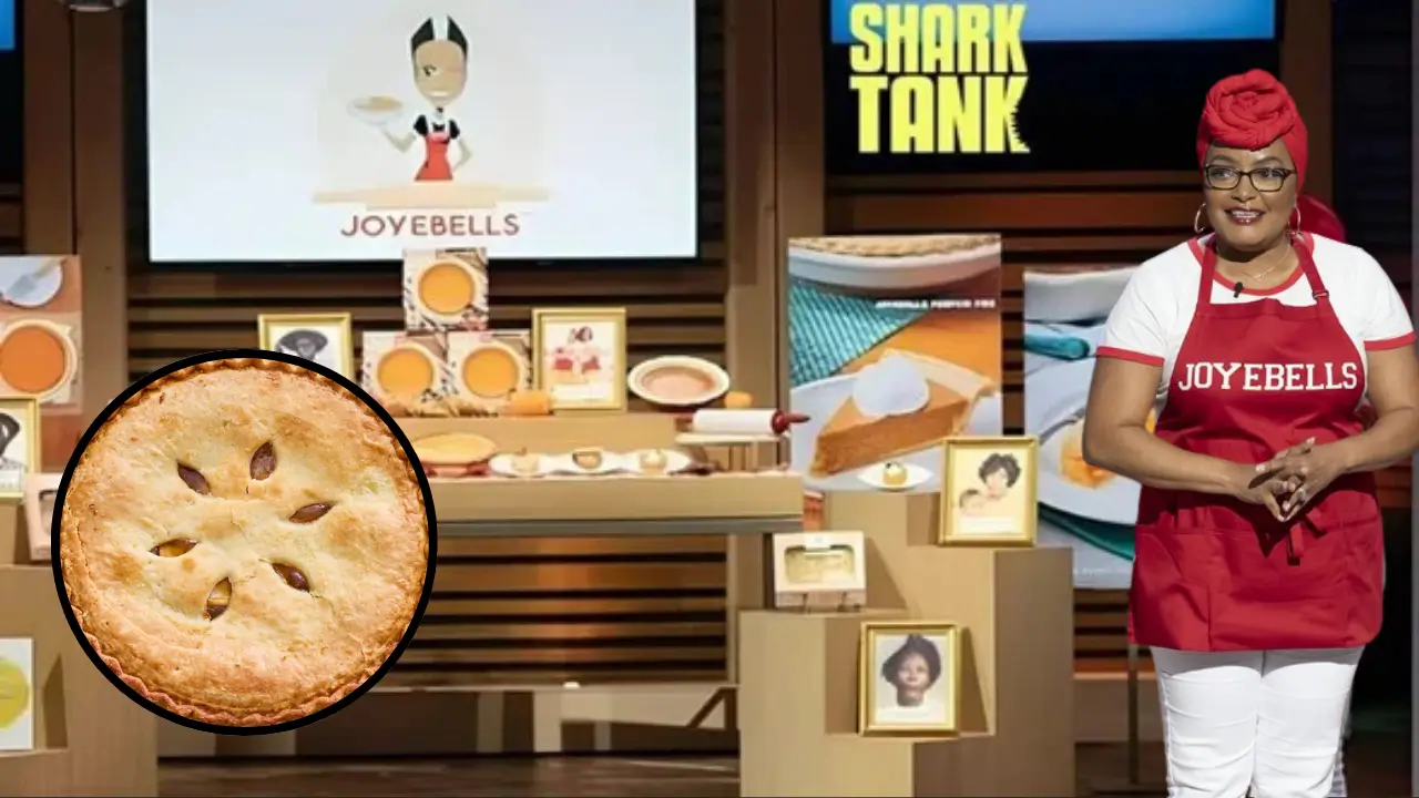 Joye Moore, founder of Joyebells, stands on the Shark Tank stage with her pies and branded display, wearing a red apron and headwrap.