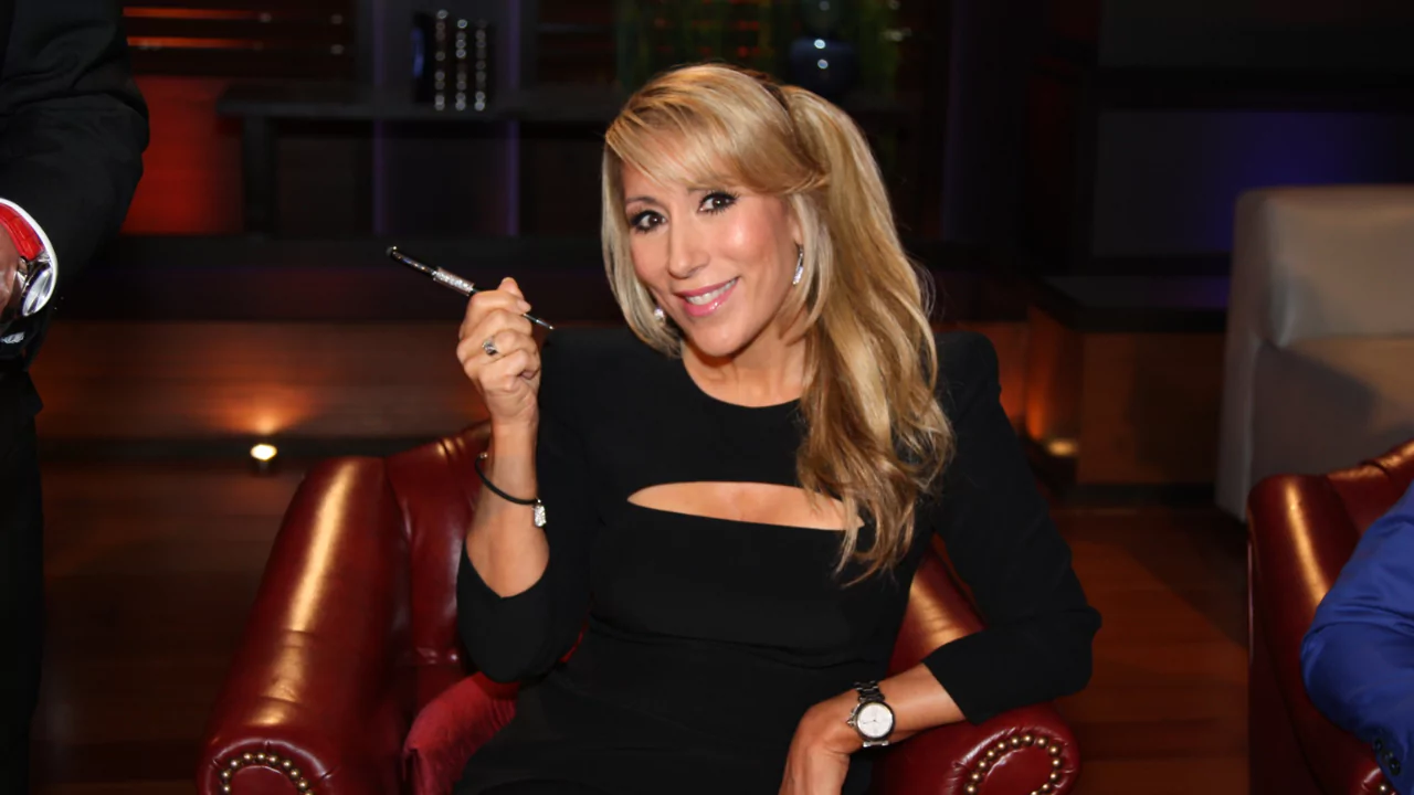 Lori Greiner sitting in Shark Tank studio holding a pen, sharing tips to get products into major retail stores like Target and Walmart