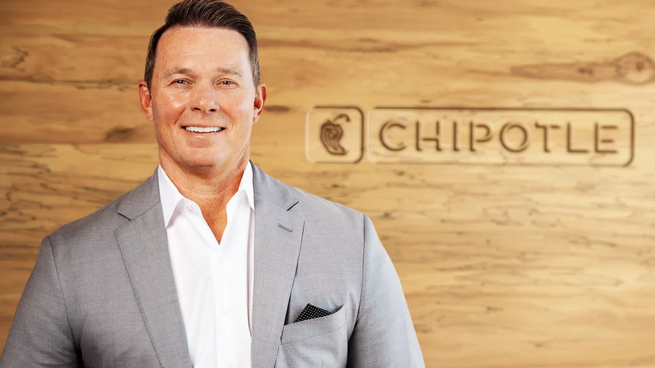 Scott Boatwright, Chief Restaurant Officer at Chipotle, standing in front of the company logo, representing Chipotle’s operational leadership.
