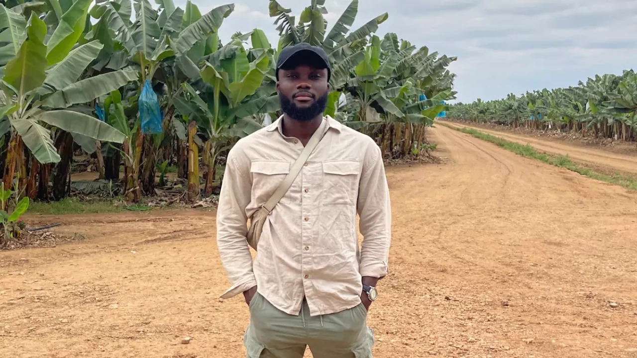 Timothy Armoo stands on a mango farm road, showcasing his unique investment journey into agriculture and lithium mining.