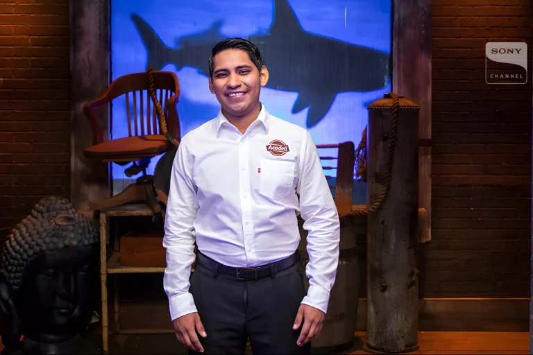 Acadeli founder smiling during his Shark Tank Mexico pitch with company logo on his shirt
