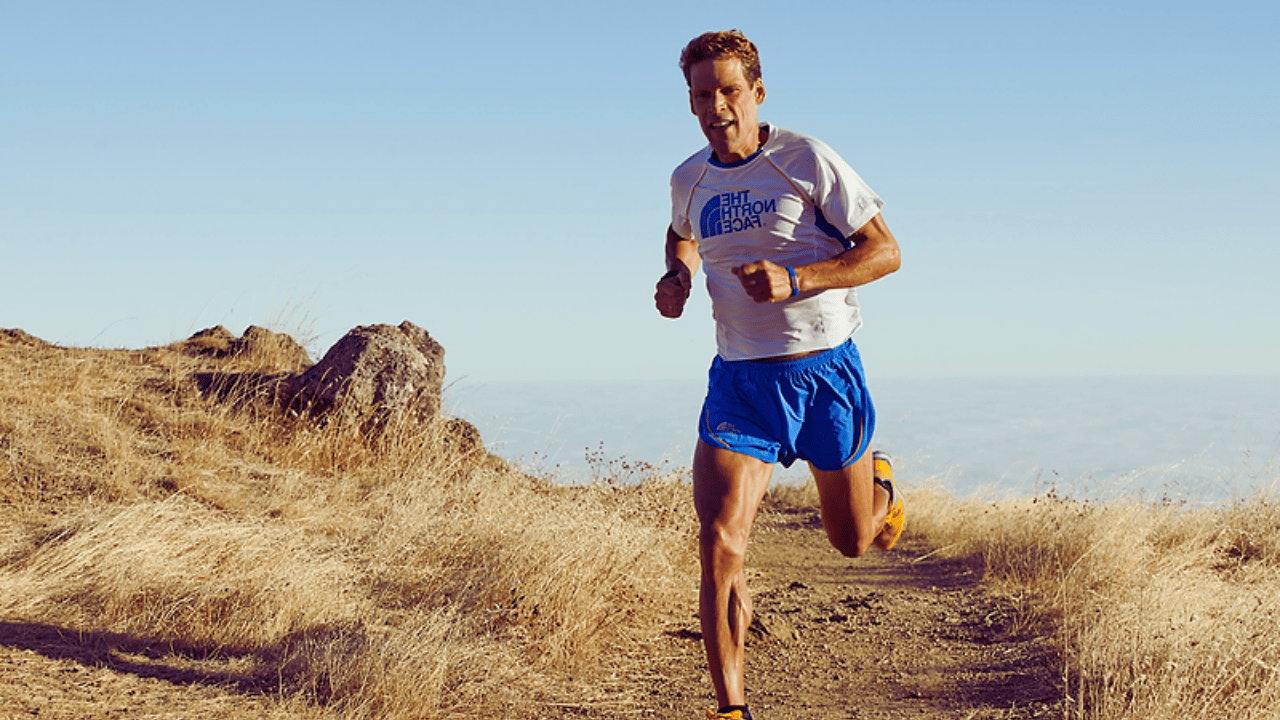 Dean Karnazes running on a mountain trail during an ultramarathon, known for completing 350 miles without sleep