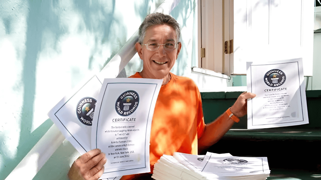 Ashrita Furman smiling while holding multiple Guinness World Records certificates, recognized as the person with the most records in history.