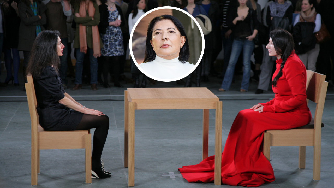 Marina Abramović sits silently across from a visitor during her 2010 MoMA performance The Artist Is Present, exploring human connection through stillness and eye contact.