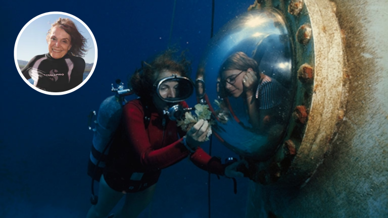 Sylvia Earle scuba diving during an underwater mission, showing coral to a researcher inside a habitat window